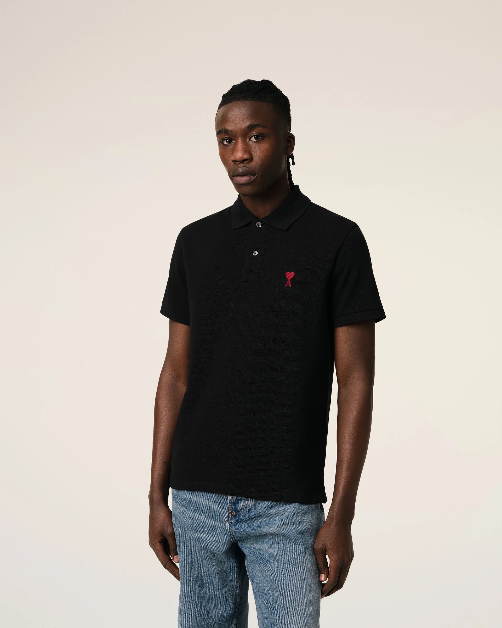 Black polo shirt with a small red logo on a beige background
