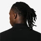 Black polo shirt with a small red logo on a beige background