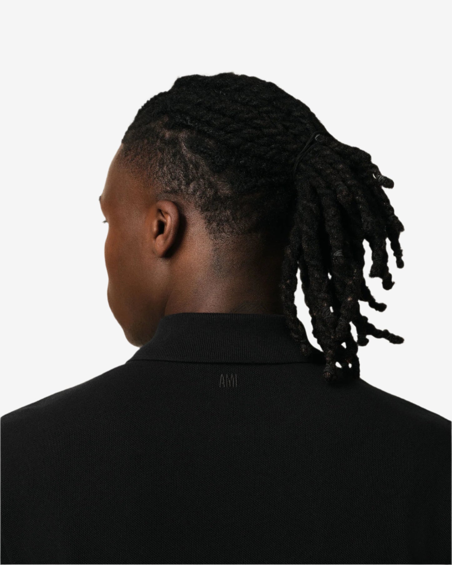 Black polo shirt with a small red logo on a beige background