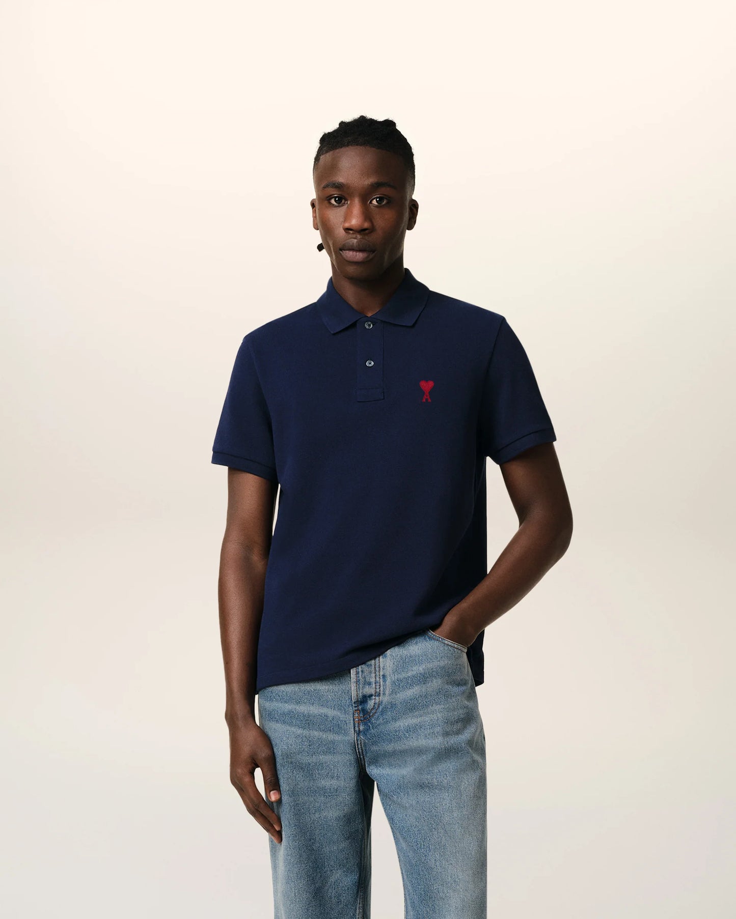 Navy blue polo shirt with a red heart logo on a beige background