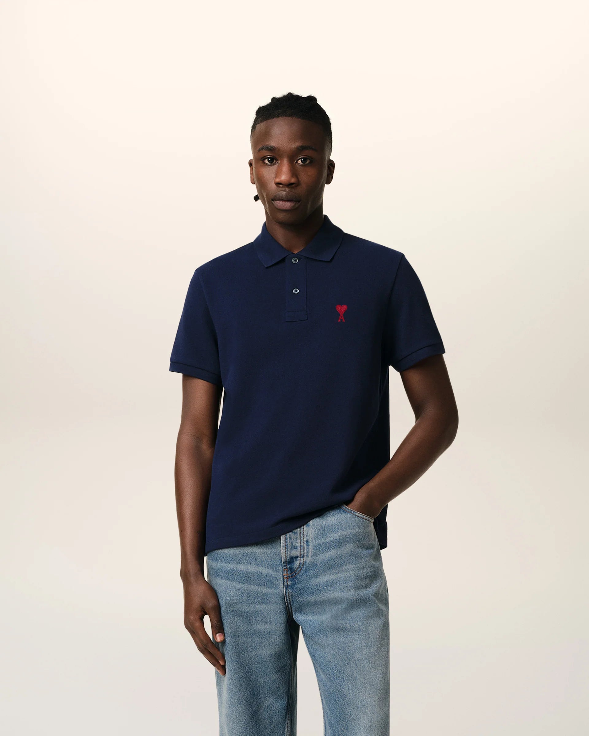 Navy blue polo shirt with a red heart logo on a beige background
