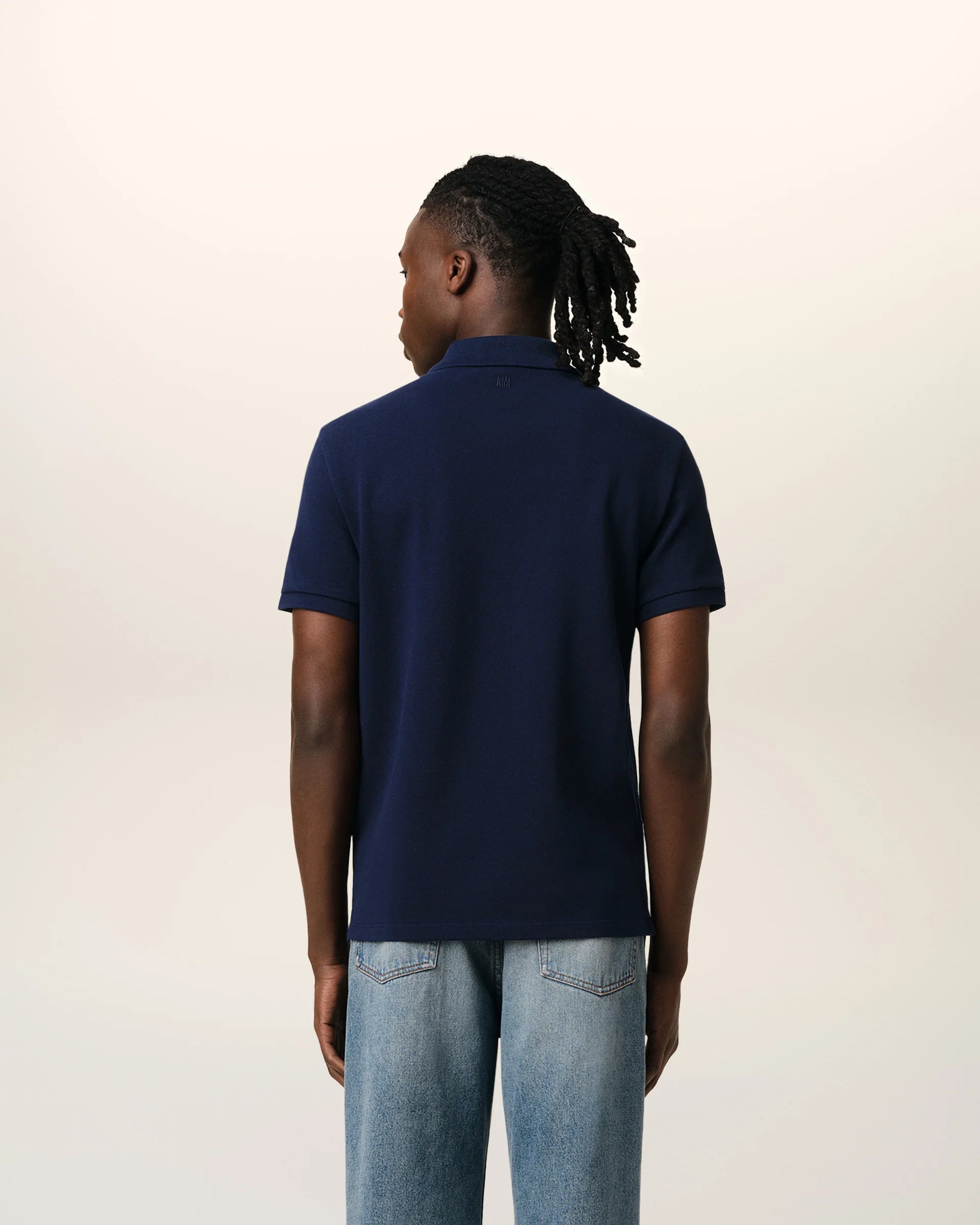 Navy blue polo shirt with a red heart logo on a beige background