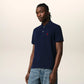Navy blue polo shirt with a red heart logo on a beige background