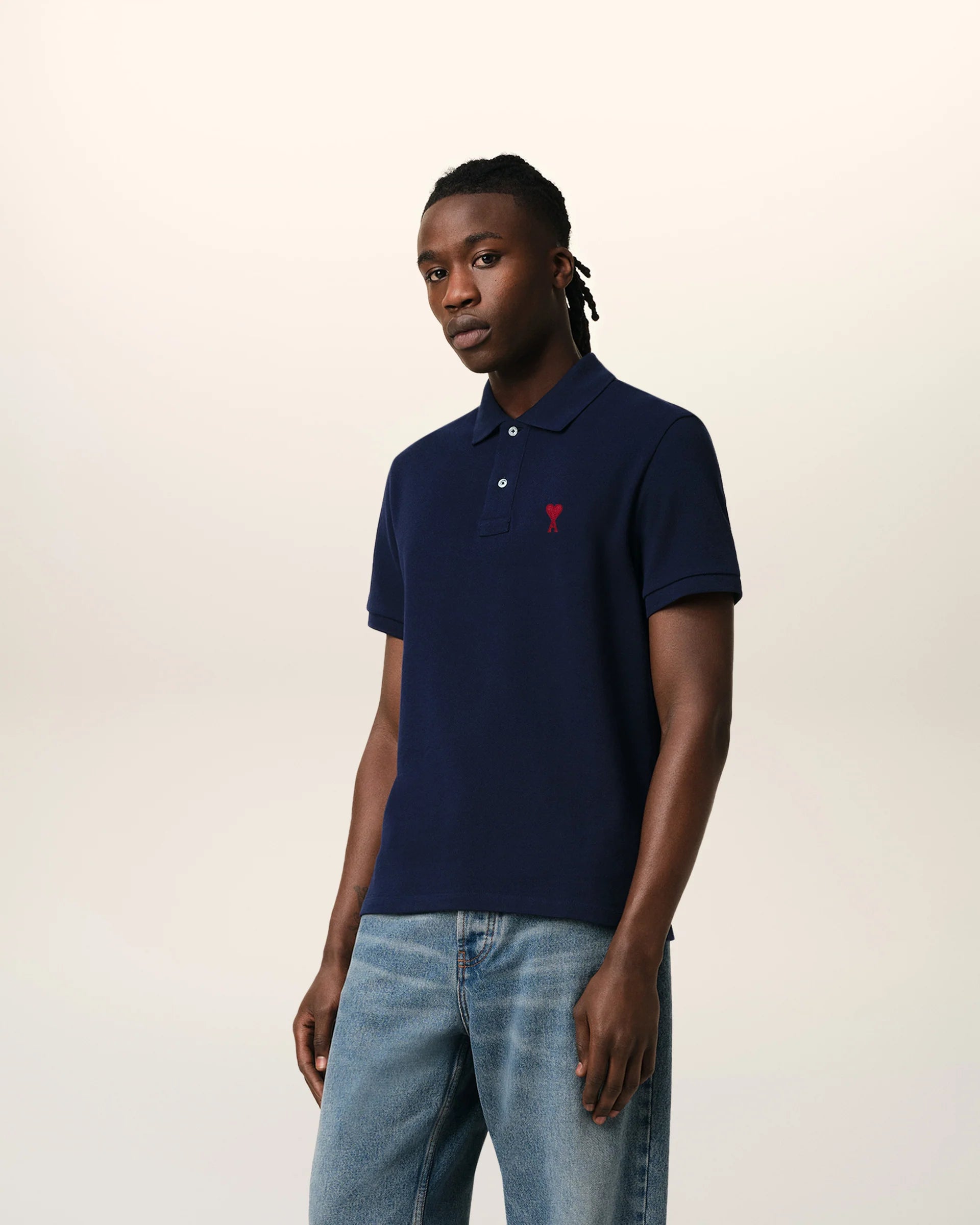 Navy blue polo shirt with a red heart logo on a beige background