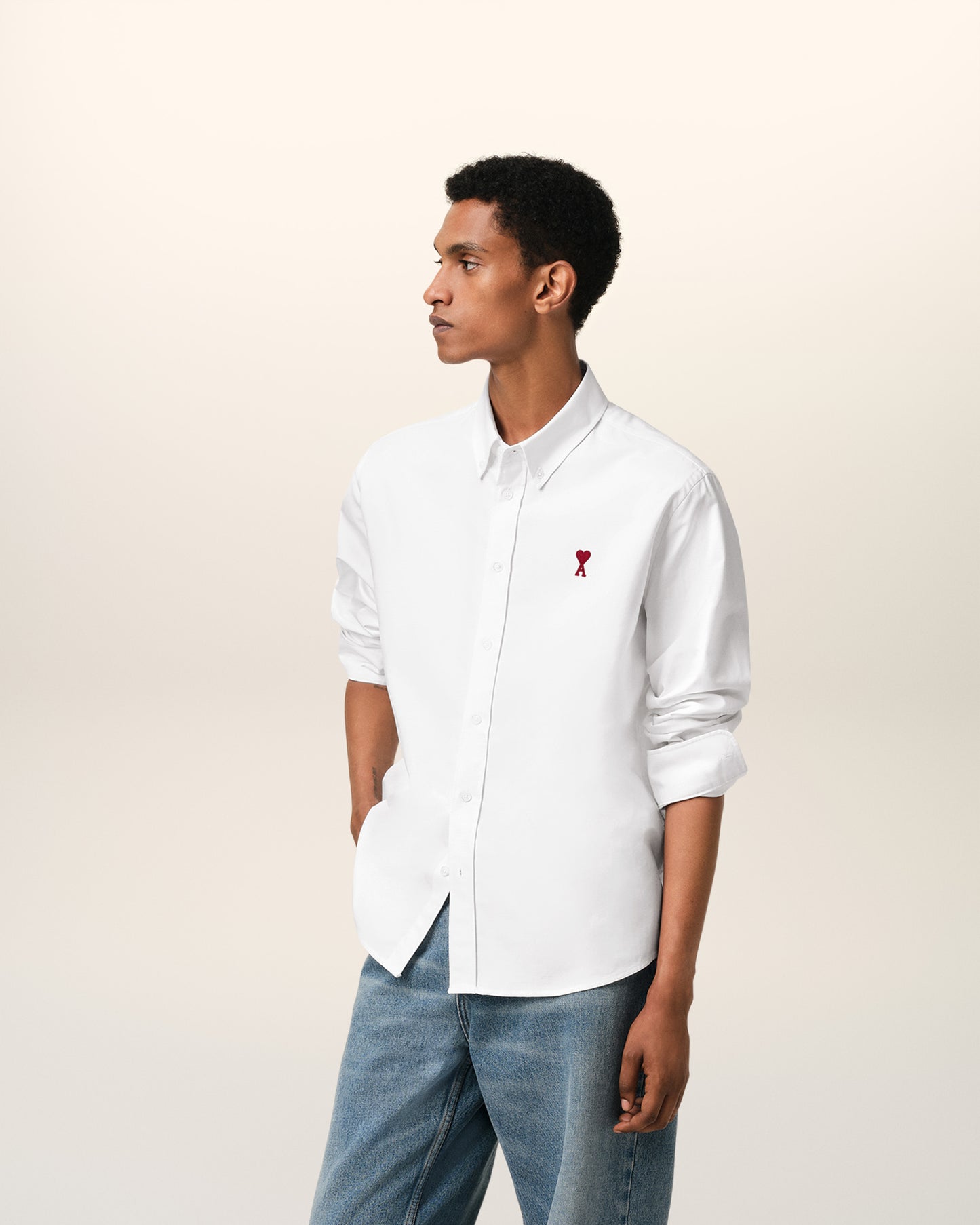 White polo shirt with a red logo on a beige background