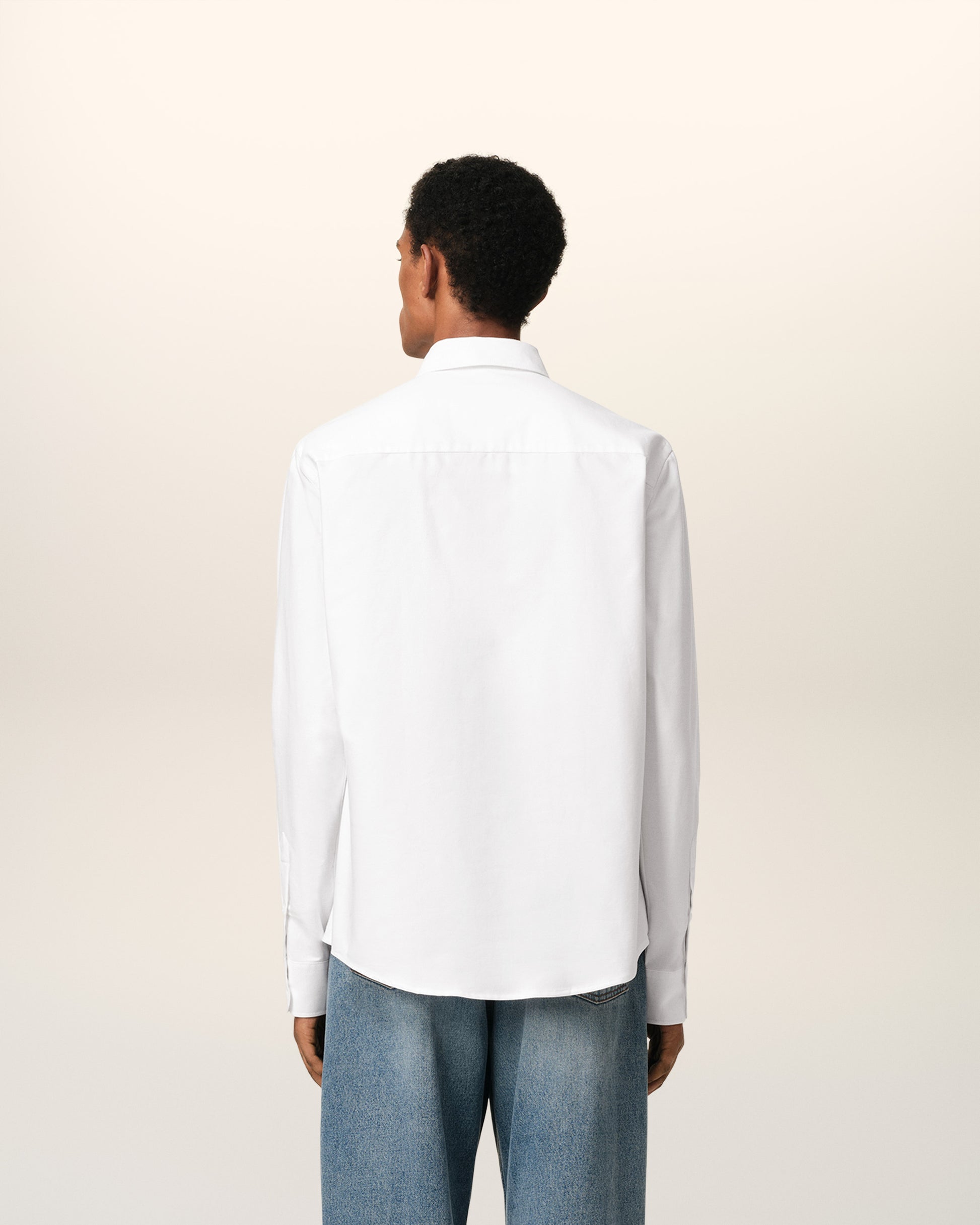 White polo shirt with a red logo on a beige background