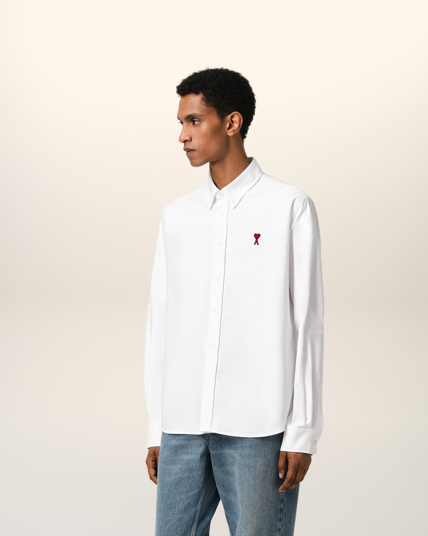 White polo shirt with a red logo on a beige background