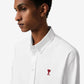 White polo shirt with a red logo on a beige background