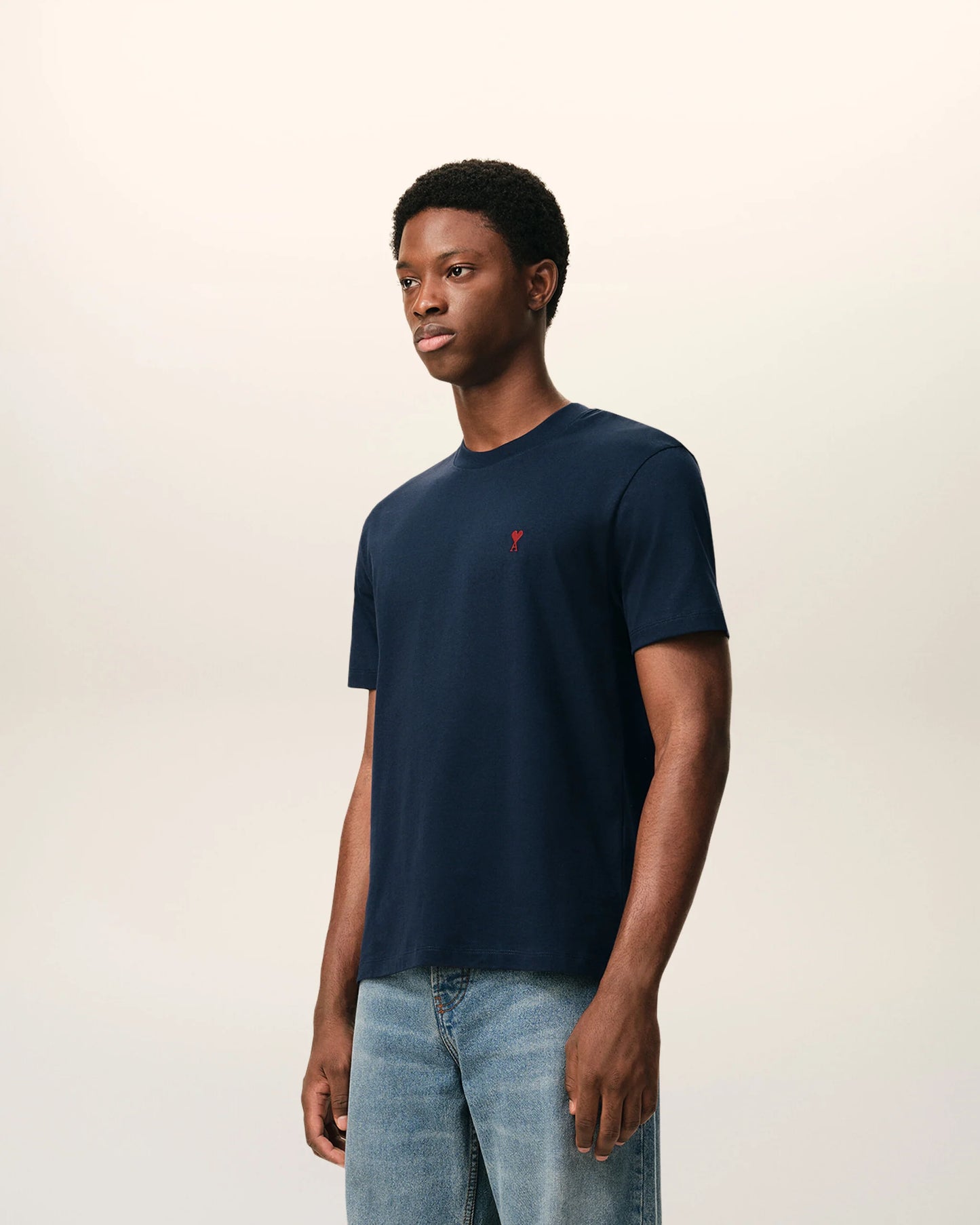 Navy blue t-shirt with a small red logo on a beige background ami paris
