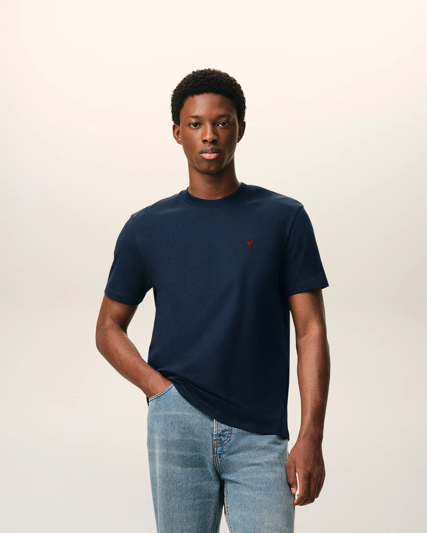 Navy blue t-shirt with a small red logo on a beige background ami paris