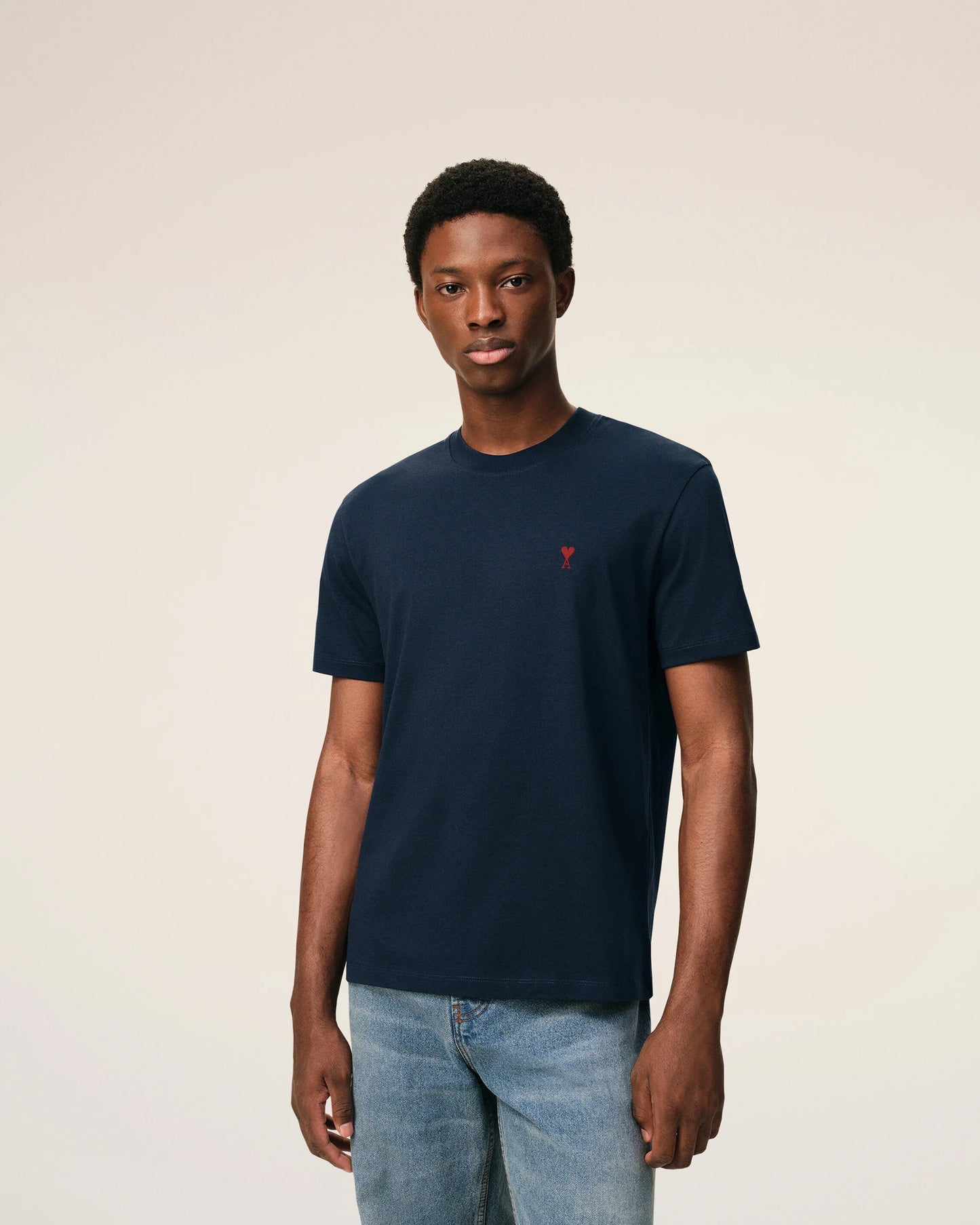 Navy blue t-shirt with a small red logo on a beige background ami paris