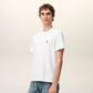 White t-shirt with a small red logo on a beige background Ami paris