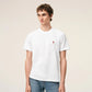 White t-shirt with a small red logo on a beige background Ami paris