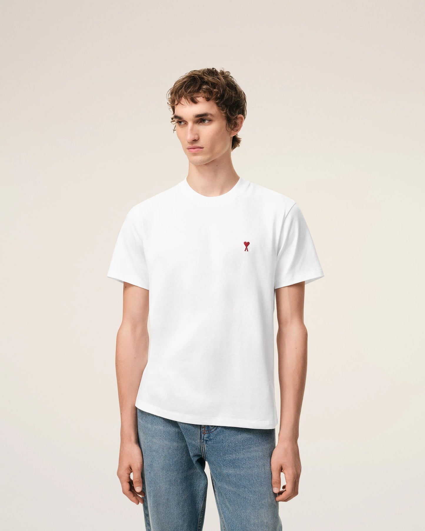 White t-shirt with a small red logo on a beige background Ami paris