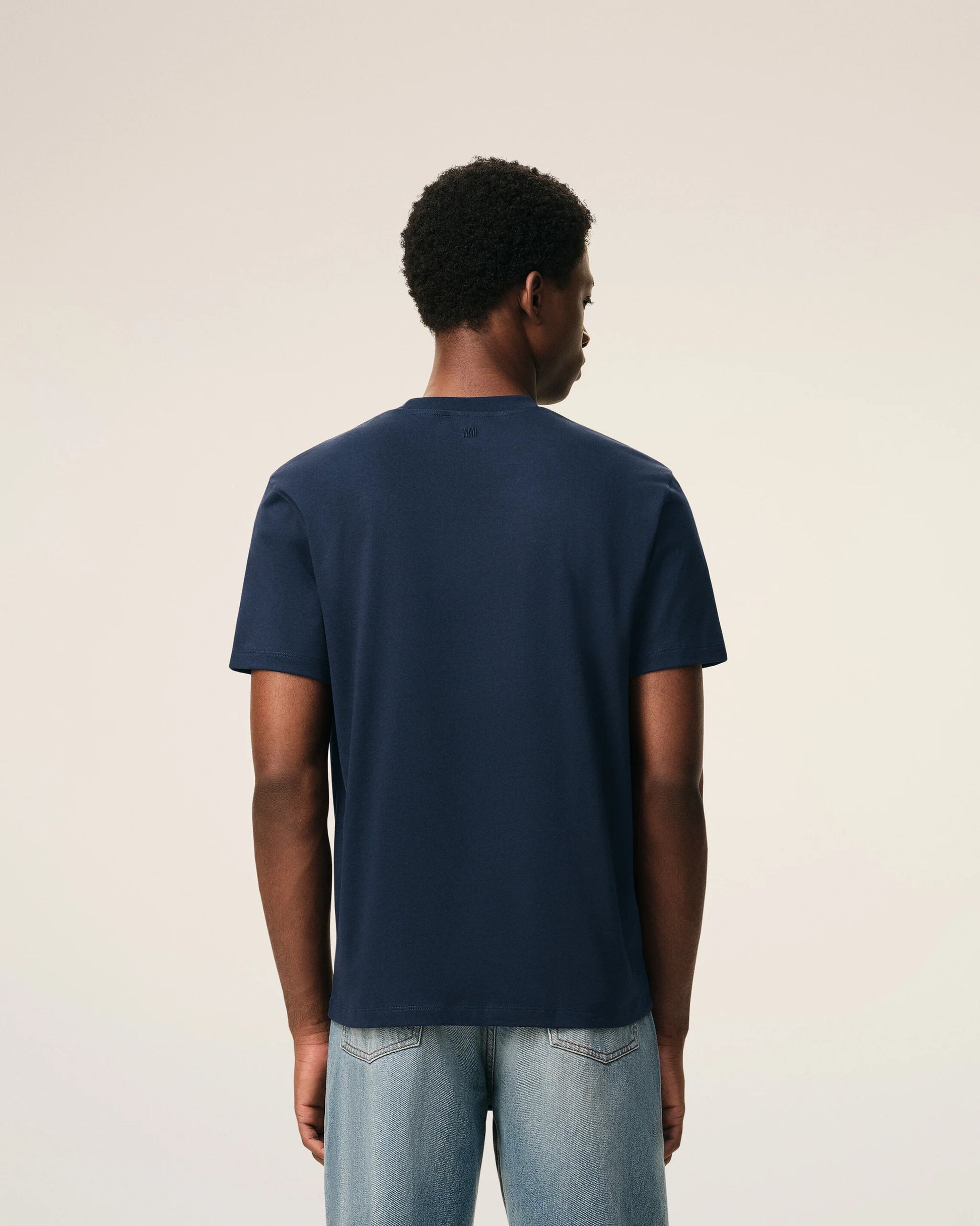 Navy blue t-shirt with a small red logo on a beige background ami paris
