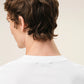 White t-shirt with a small red logo on a beige background Ami paris