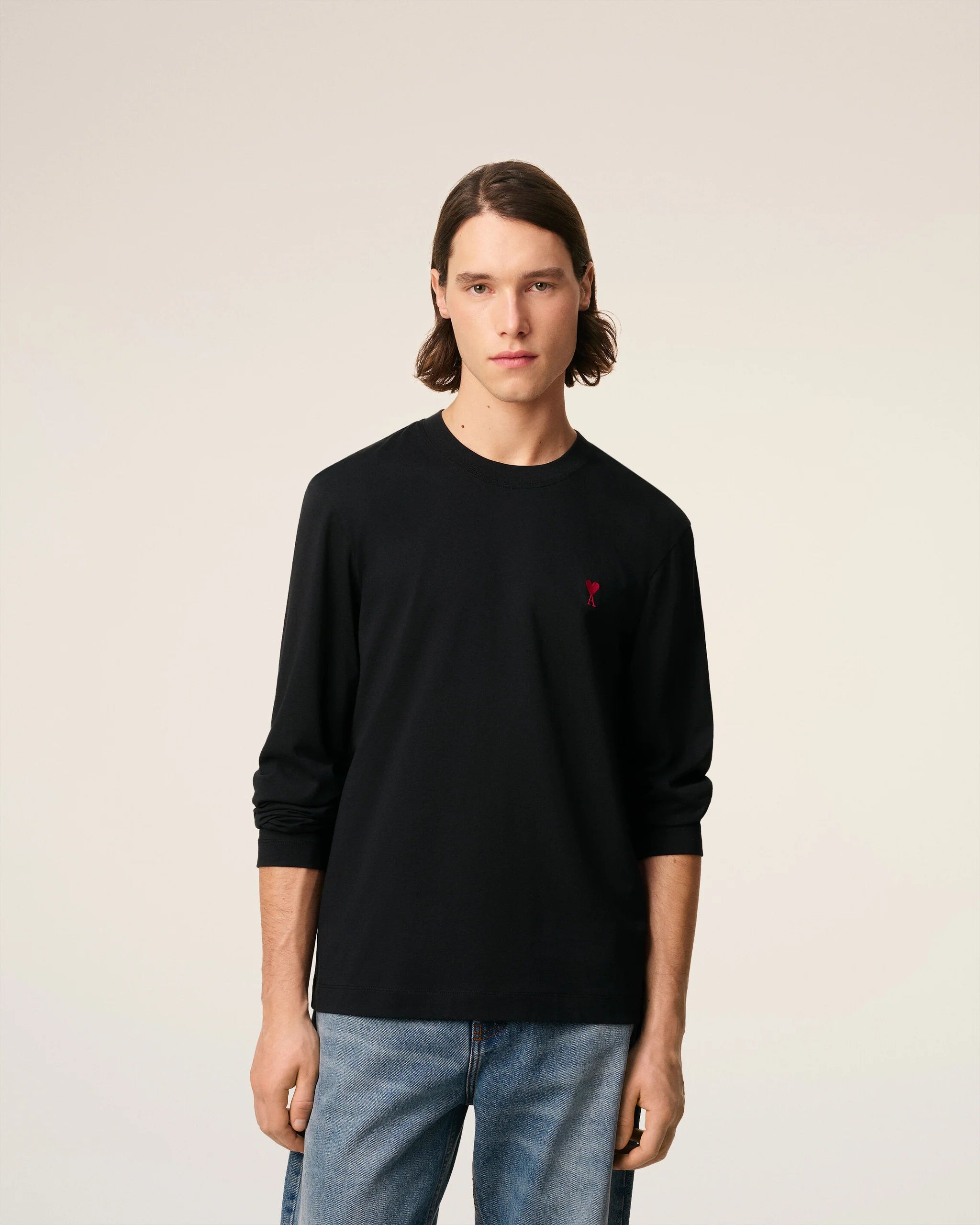 Black long-sleeve shirt with a red logo on a beige background