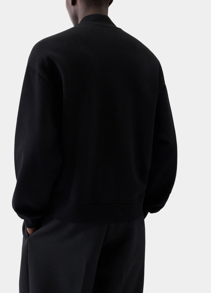 Black varsity jacket with a logo on the chest against a white background