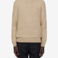 Person wearing a beige sweater and black pants on a white background