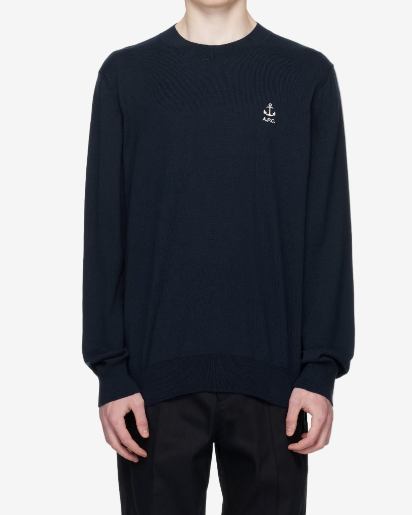 Person wearing a black sweater with a small logo on a white background