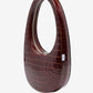 Brown crocodile-patterned handbag on a white background