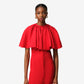 Red dress with cape worn by a model on a plain background