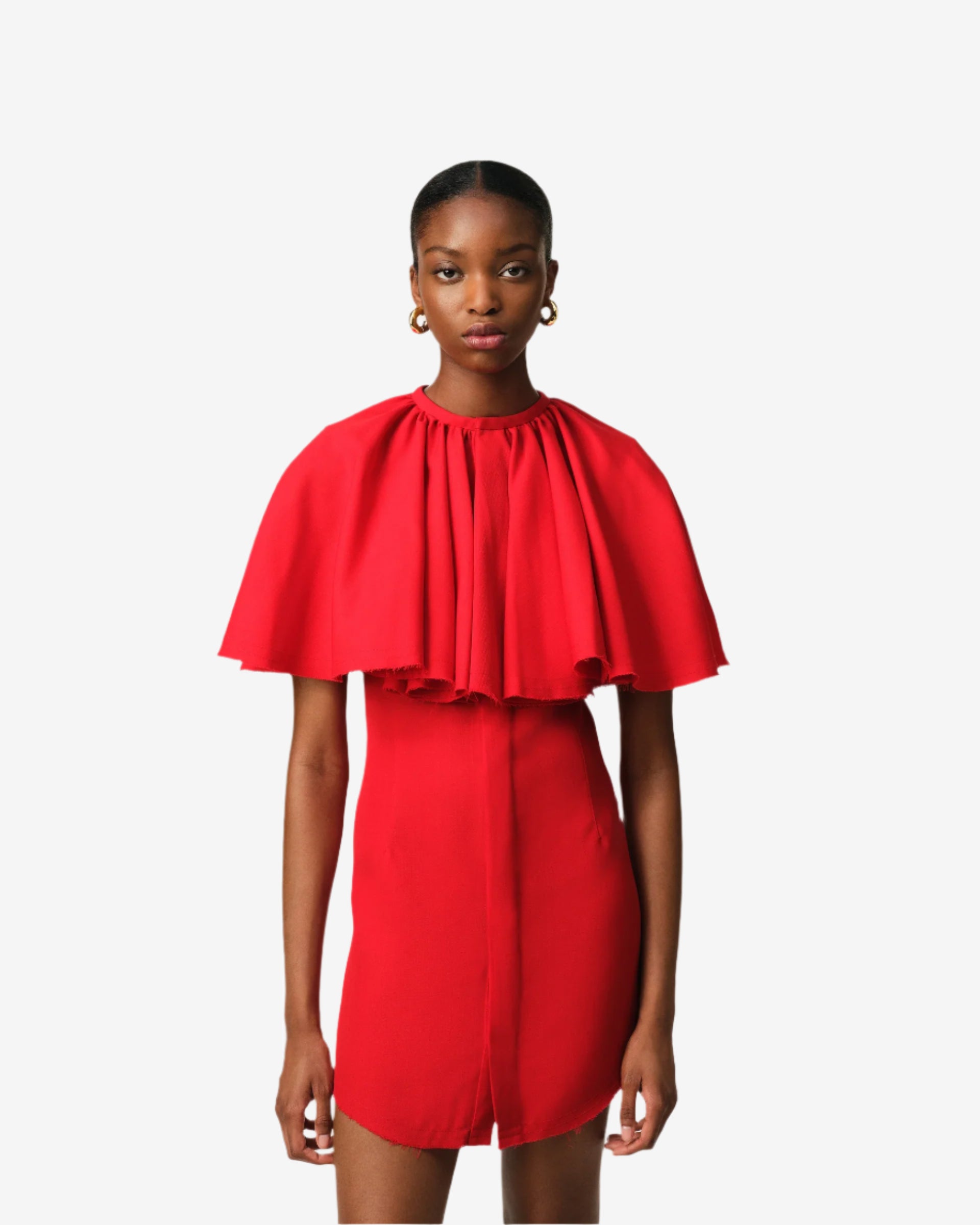 Red dress with cape worn by a model on a plain background