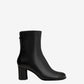Black ankle boot on a light beige background
