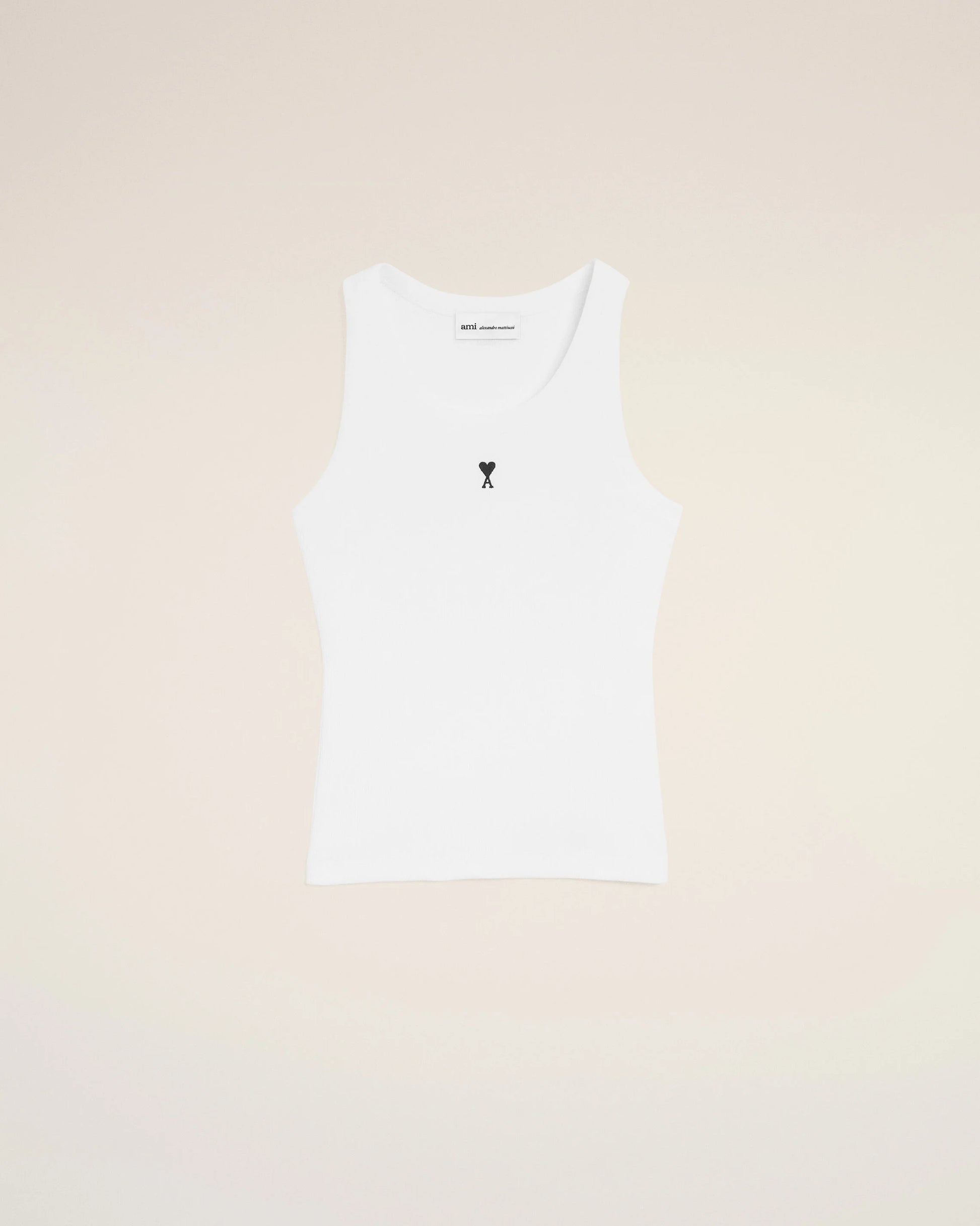 White tank top with a small black design on a beige background