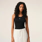Black tank top with a small white logo on a beige background