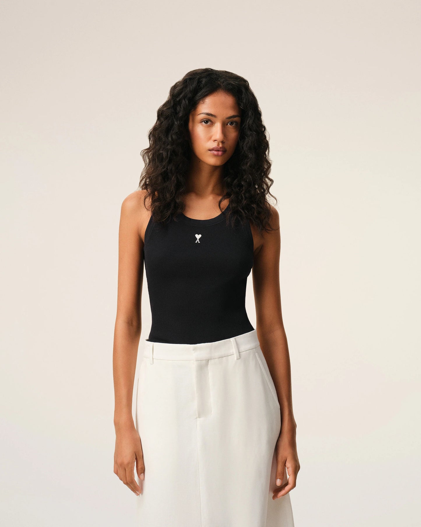 Black tank top with a small white logo on a beige background