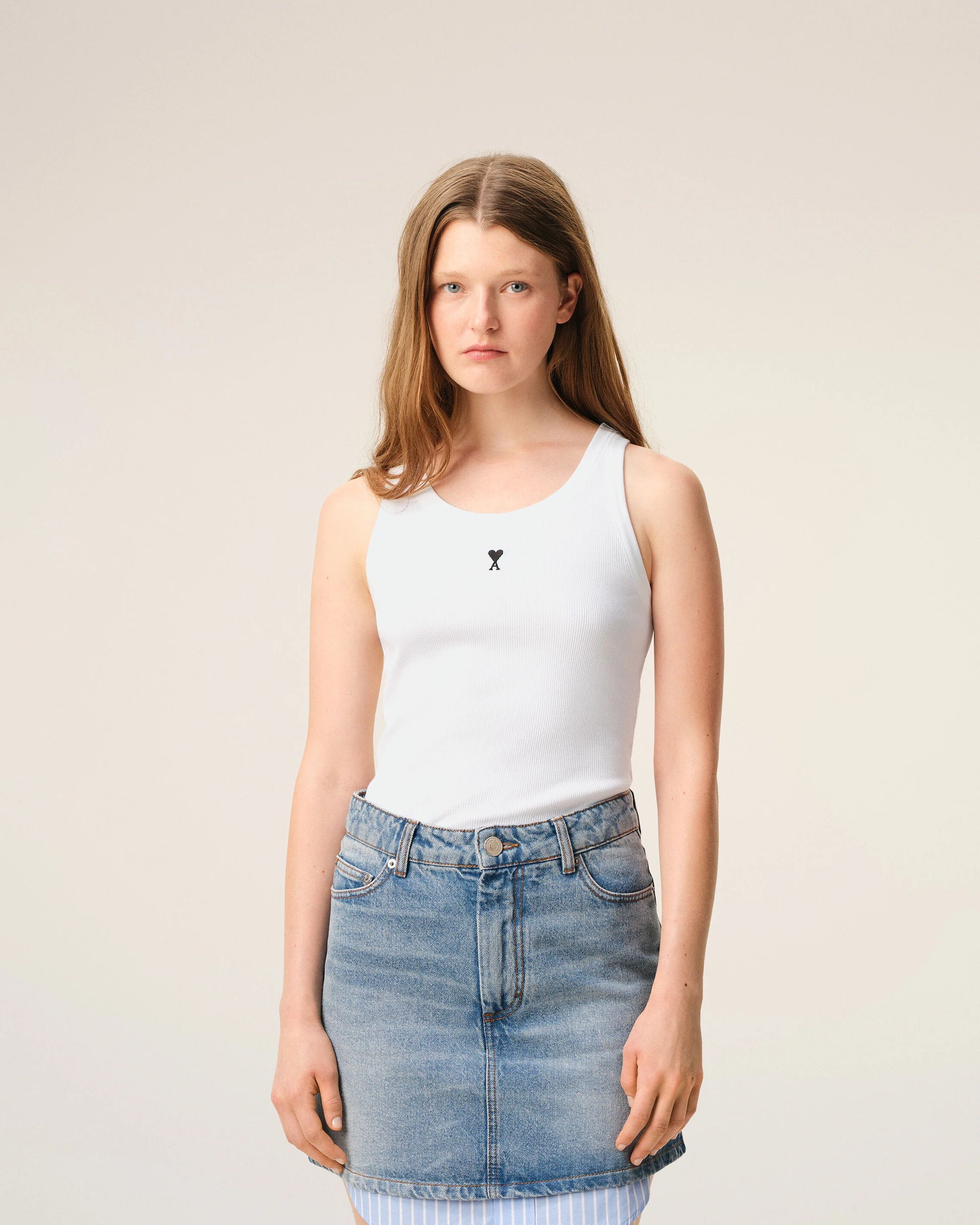 White tank top with a small black design on a beige background