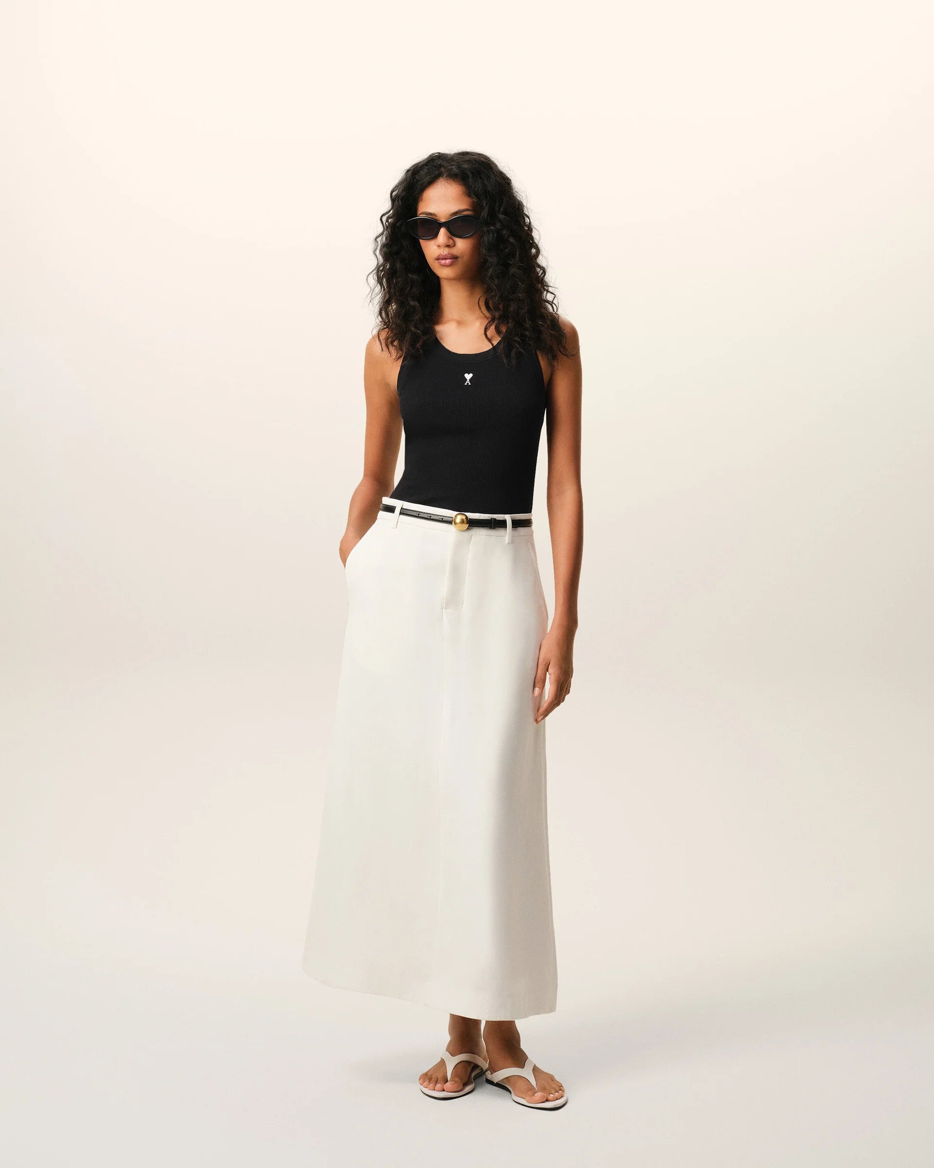 Black tank top with a small white logo on a beige background