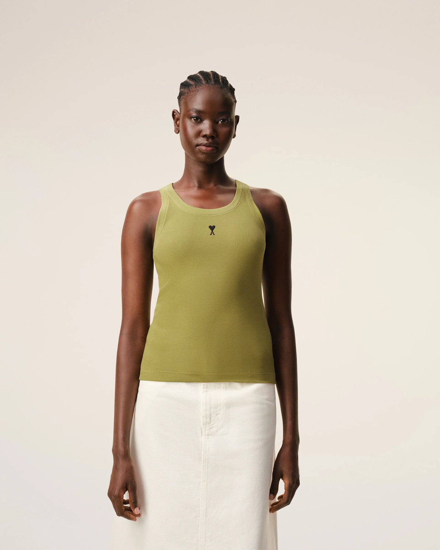 Green tank top with a small black logo on a beige background