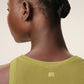 Green tank top with a small black logo on a beige background
