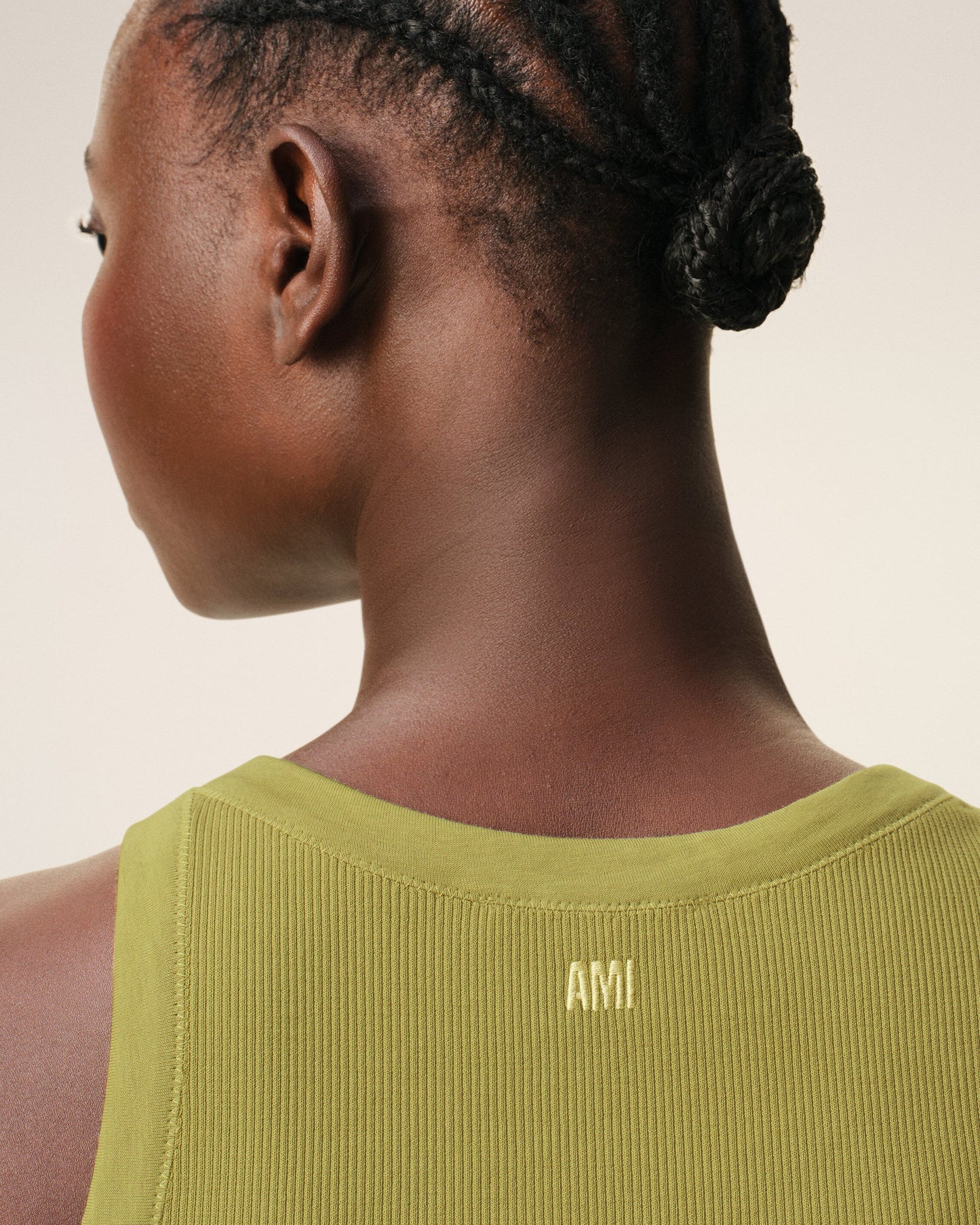 Green tank top with a small black logo on a beige background