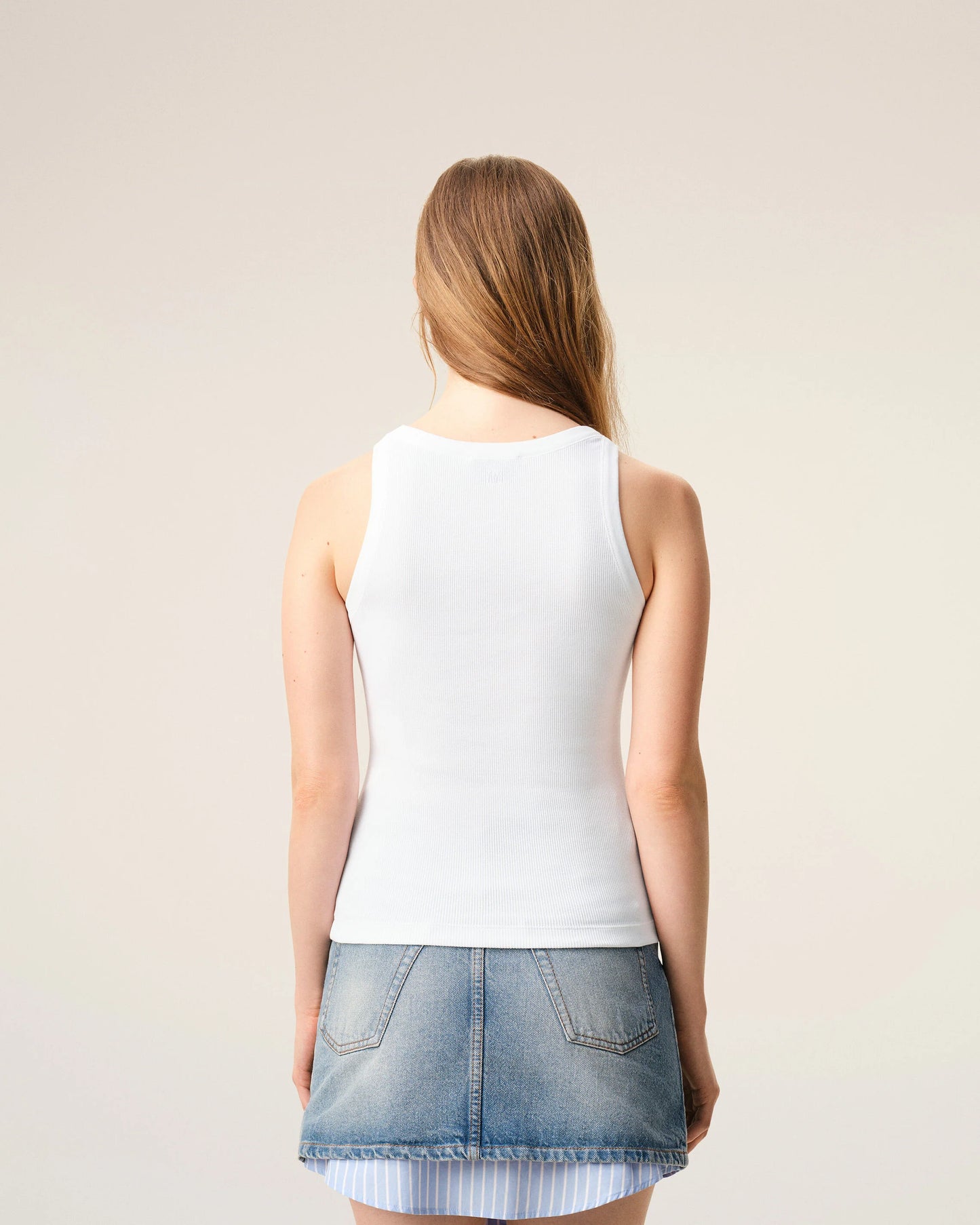 White tank top with a small black design on a beige background