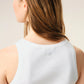 White tank top with a small black design on a beige background