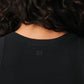 Black tank top with a small white logo on a beige background