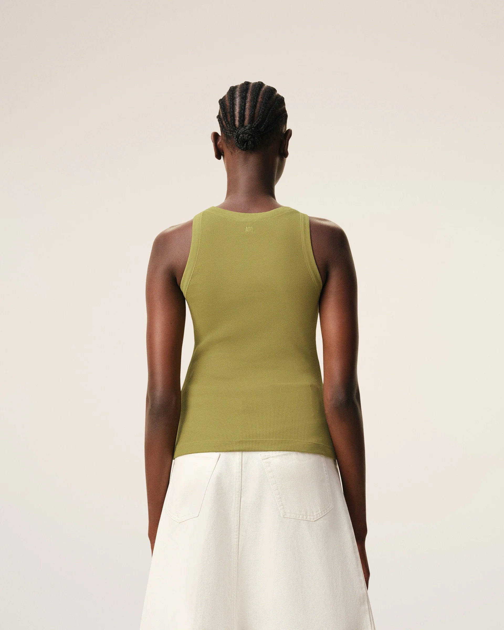 Green tank top with a small black logo on a beige background