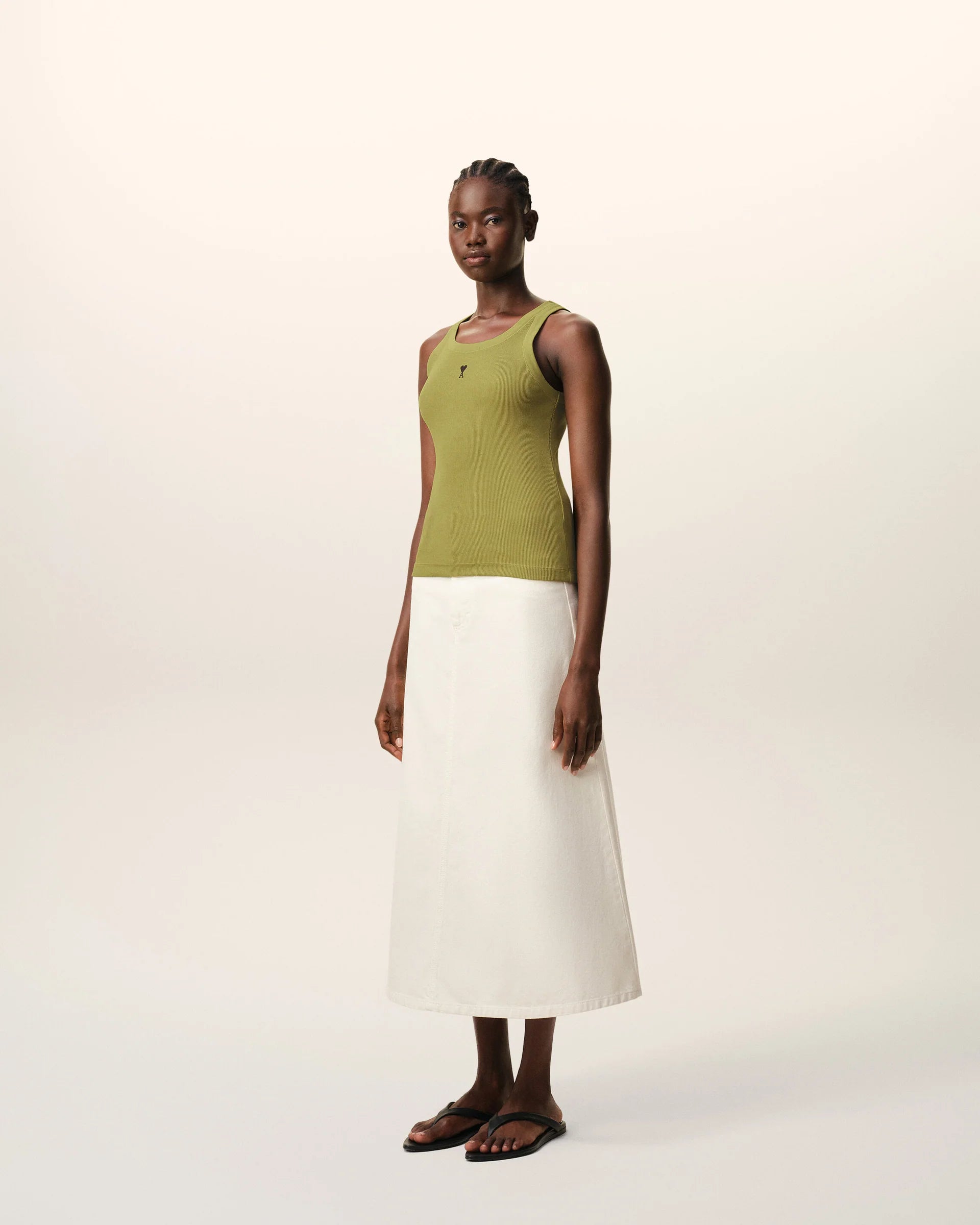 Green tank top with a small black logo on a beige background