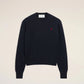 Black sweater with a red heart emblem on a beige background