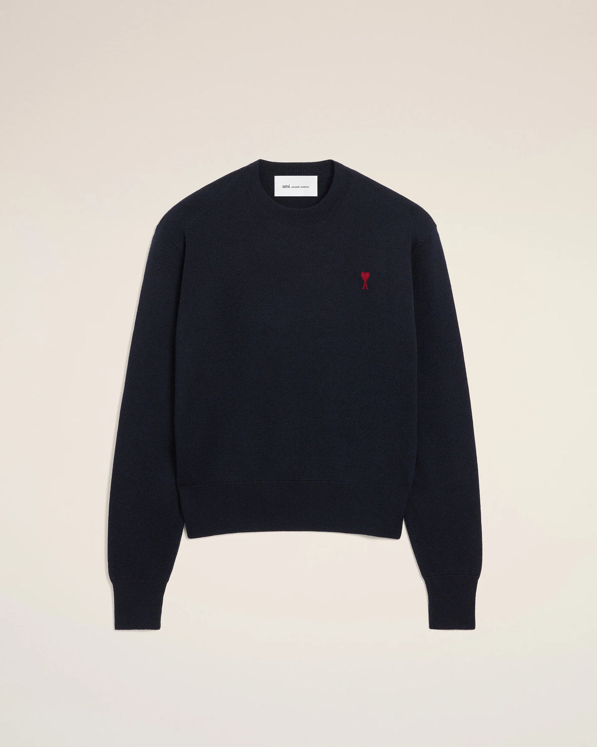 Black sweater with a red heart emblem on a beige background