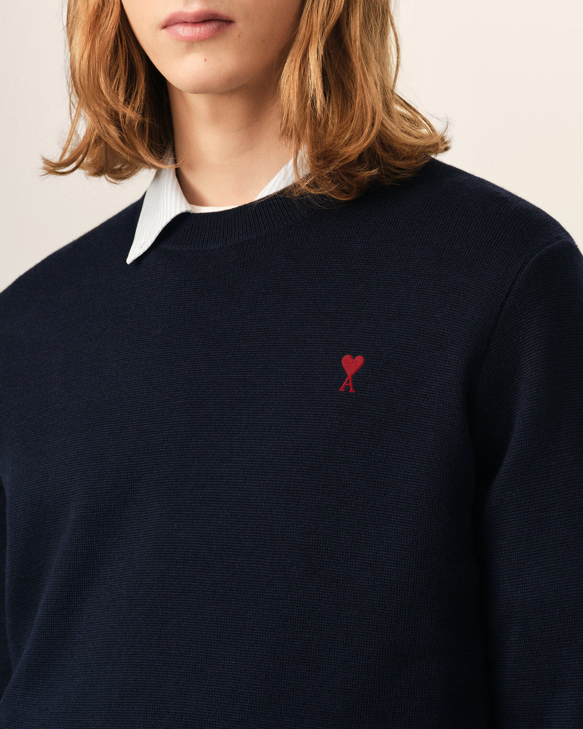 Black sweater with a red heart emblem on a beige background
