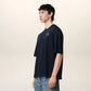Navy blue t-shirt with 'ami' logo on a beige background ami paris