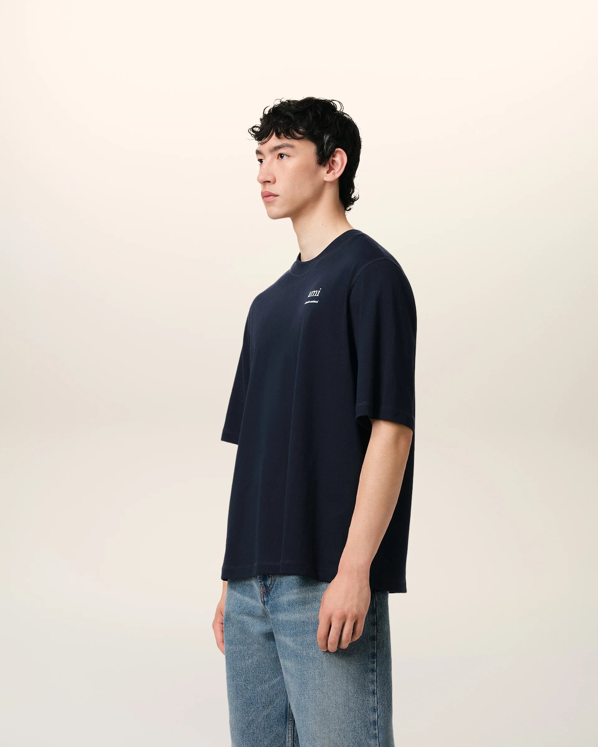 Navy blue t-shirt with 'ami' logo on a beige background ami paris