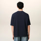 Navy blue t-shirt with 'ami' logo on a beige background ami paris