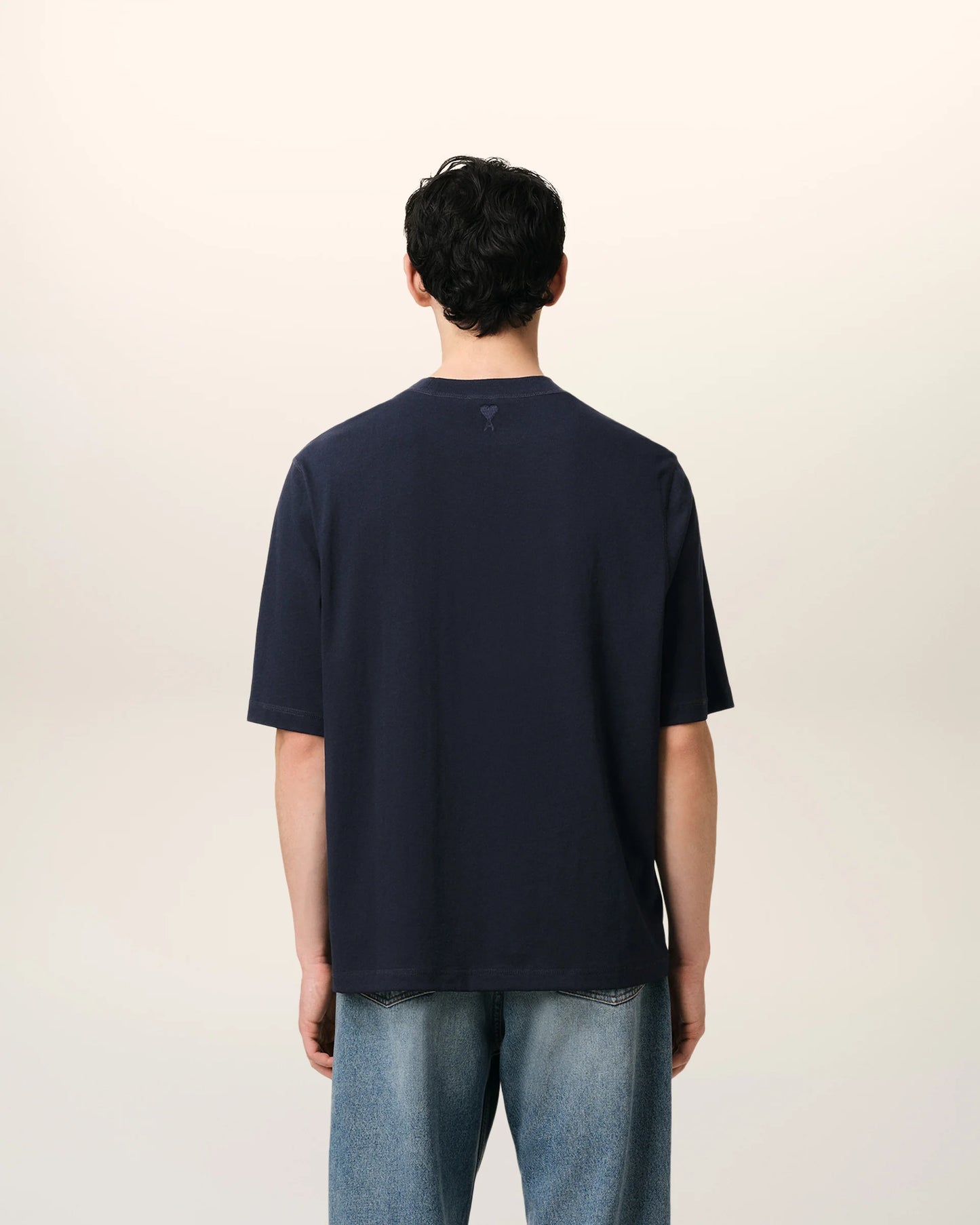Navy blue t-shirt with 'ami' logo on a beige background ami paris