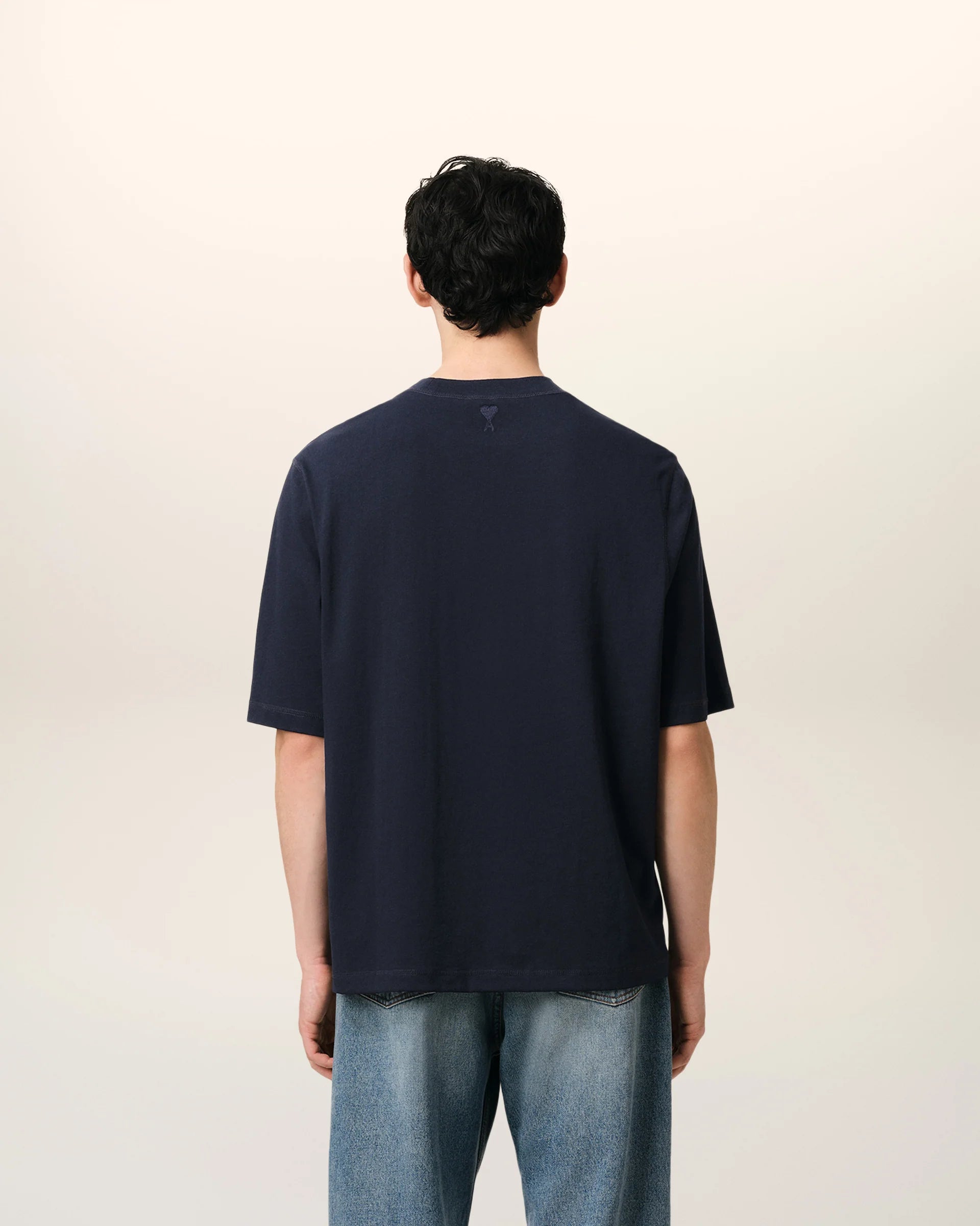 Navy blue t-shirt with 'ami' logo on a beige background ami paris