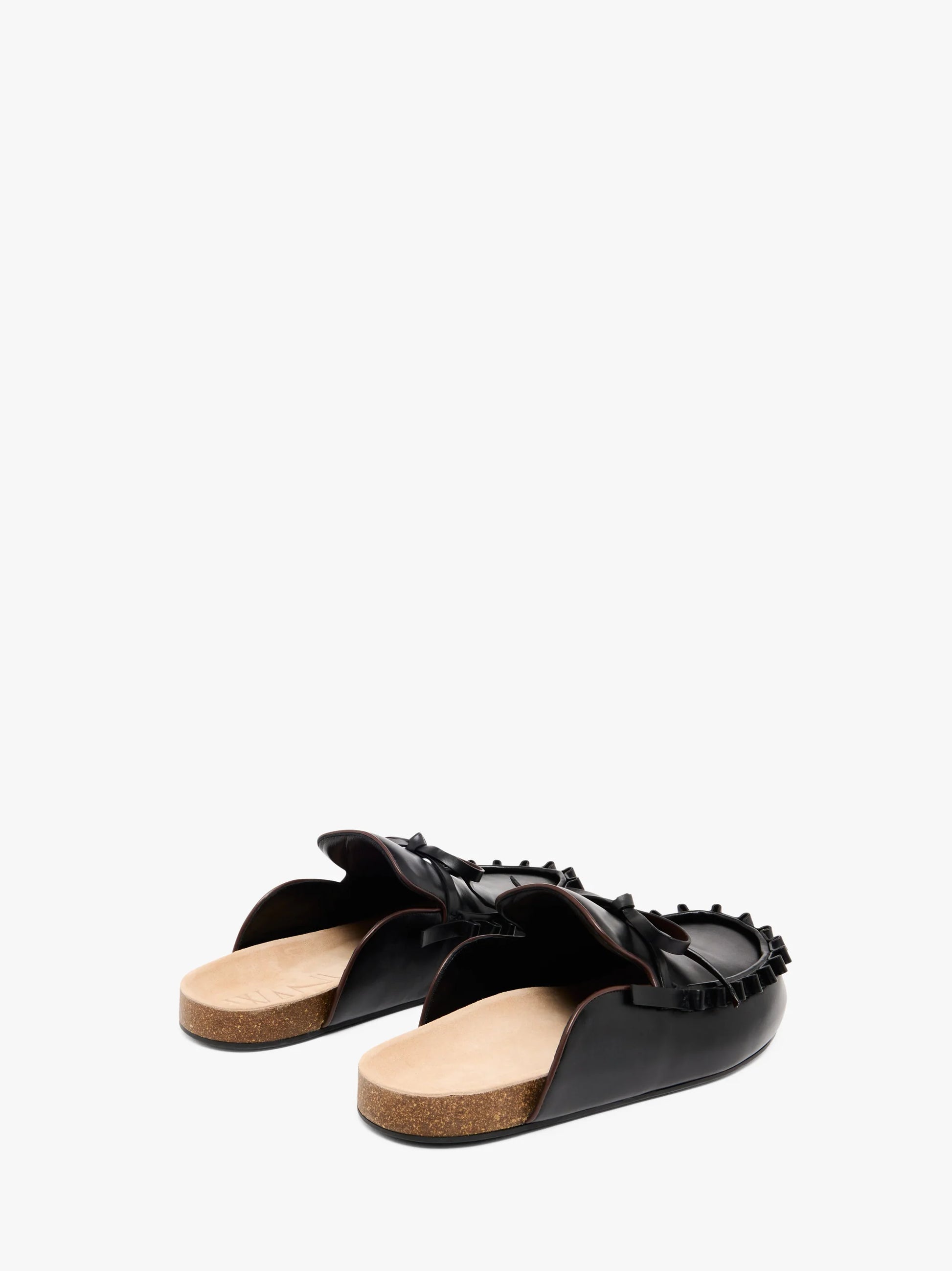 Pair of black leather mules with beige soles on a white background